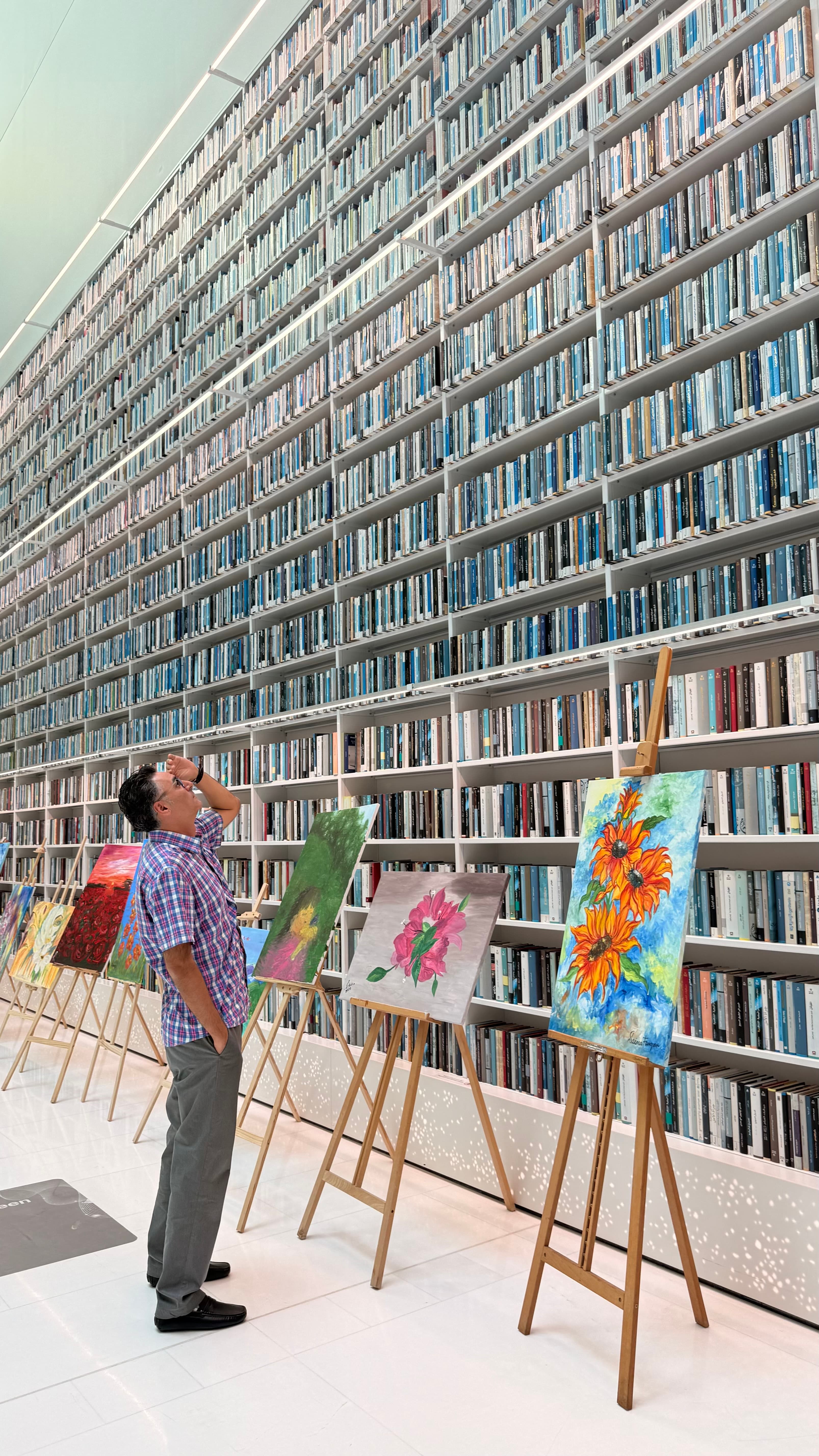 Vast library shelving with a small art exhibition in the foreground